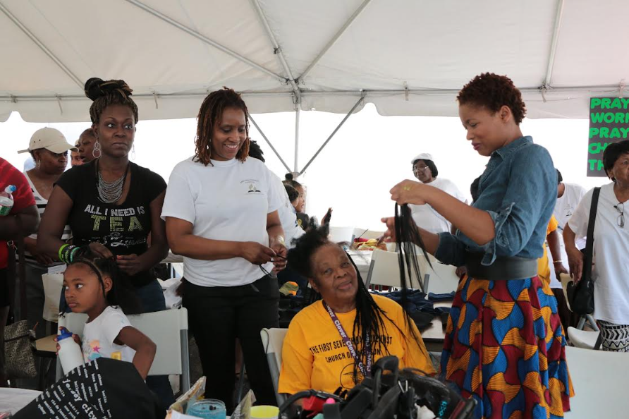 Black children receiving free haircuts and styling from local barbers and stylists at Sisters for Good back to school event